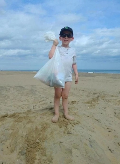 Pequeño paso su día en la playa limpiándola