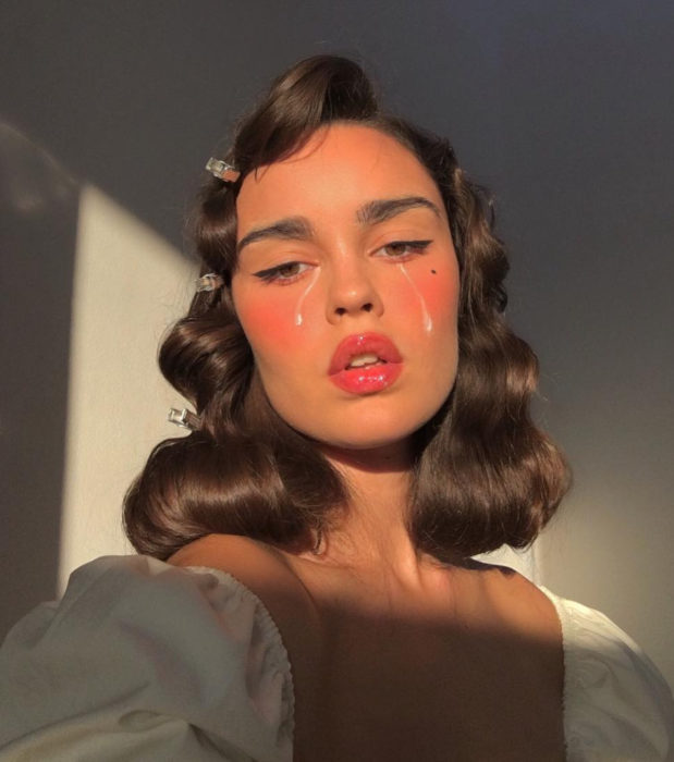 Looks aesthetic con cabello corto, castaño, ondulado con peinado vintage, mujer con maquillaje natural y detalles de lágrimas pintadas