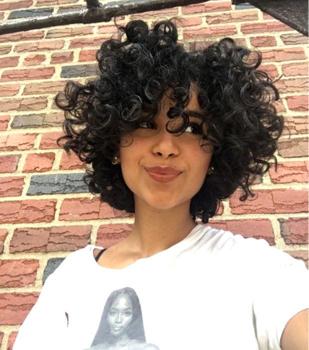 Looks aesthetic con cabello corto color castaño, rizado, mujer morena sonriendo