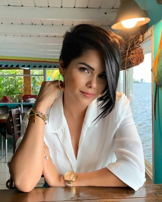 Mujer sentada con blusa blanca con cabello estilo pixie con un lateral más largo