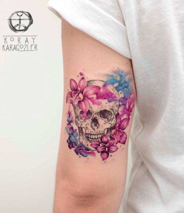Diseños bonitos de tatuajes de acuarelas; tatuaje de calavera con flores en el brazo