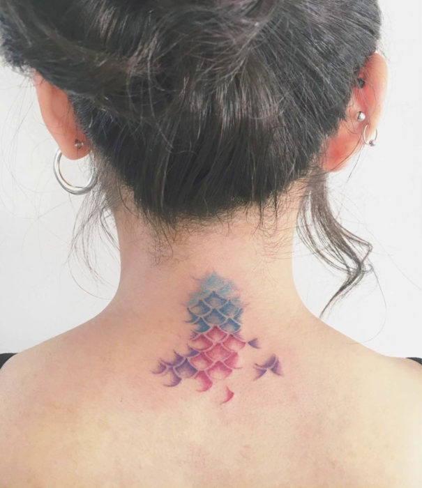 Diseños bonitos de tatuajes de acuarelas; tatuaje de escamas de sirena en colores pastel en la espalda, cuello