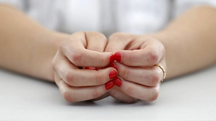 Chica usando esmalte en tono rojo; 4 Motivos por los que podrías morder tus uñas constantemente 