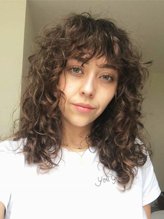 Mujer castaña con cabello rizado y corte shag