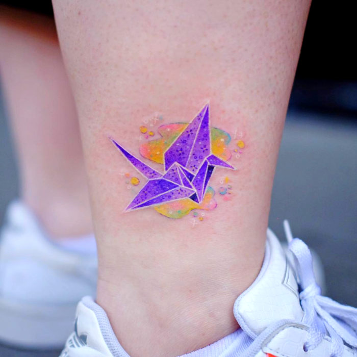 Tatuadora crea tatuajes bellos; tatuaje de grulla de origami en el tobillo