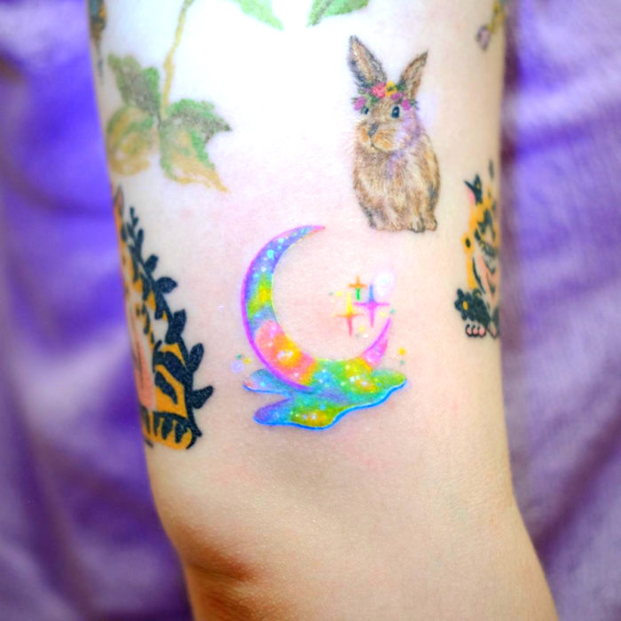 Tatuadora crea tatuajes bellos; tatuaje de media luna con colores pastel, conejo y estrellitas en el brazo