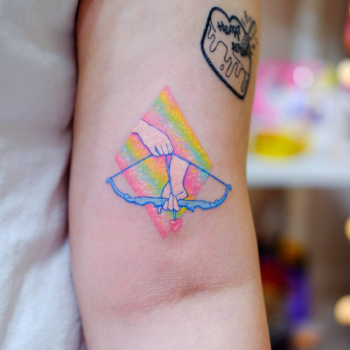 Tatuadora crea tatuajes encantadores; tatuaje de arco con flecha de querubín en el brazo