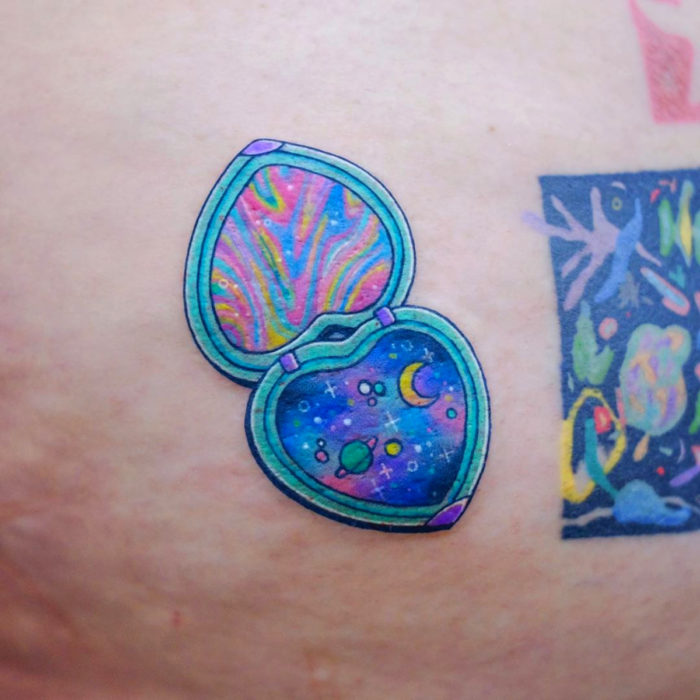 Tatuadora elabora tatuajes reflexivos; tatuaje de espejo de mano con universo y planetas