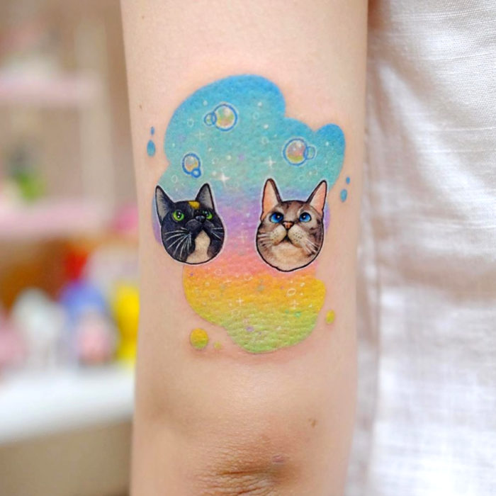 Tatuadora crea tatuajes adorables; tatuaje de gatos en arcoíris en el brazo