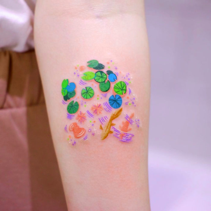 Tatuadora crea tatuajes serenos; tatuaje de hojas de nenúfar y peces koi en el brazo