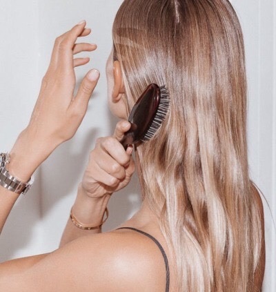 chica rubia cepillando su cabello 