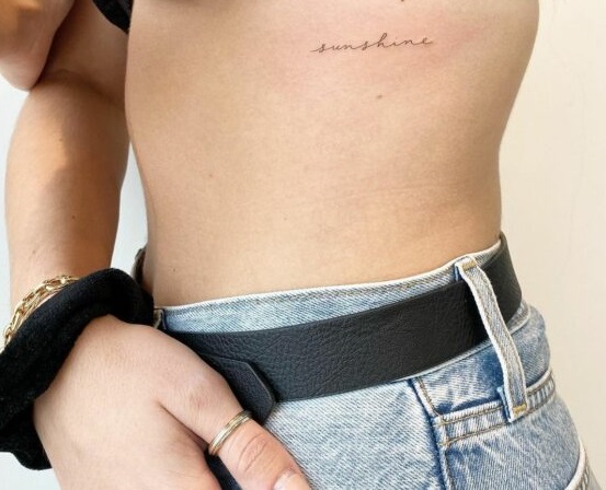 Tatuaje de frase en inglés en la costilla para chicas