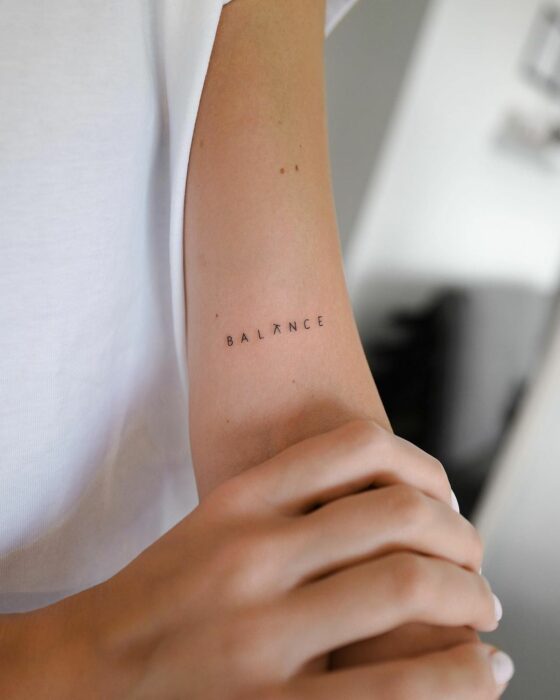 Tatuaje de palabra "balance" en el brazo