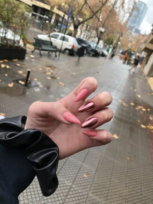 Chica con manicura stiletto en color rosa con efecto metálico