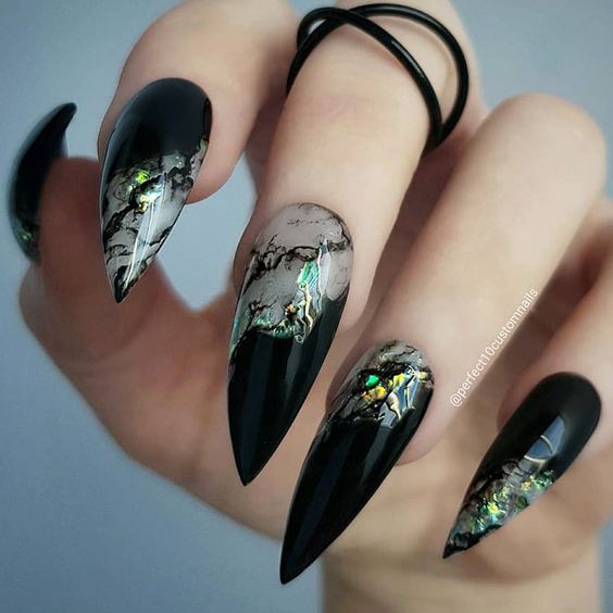 Chica con manicura stiletto en color negro con estampado metalizado