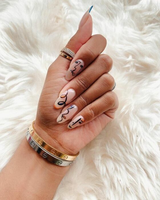 Chica con manicura stiletto en color nude decoradas con arte