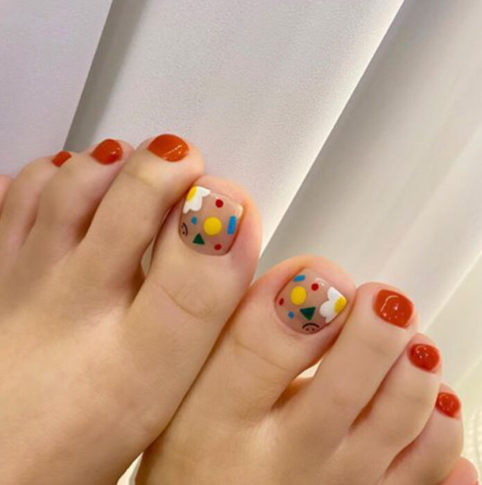 Pedicura en colores naranja, azul, amarillo y blanco