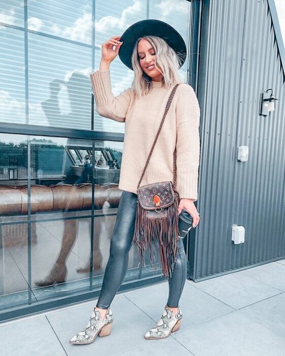 Chica usando botas pitón con jeans denim, suéter color beige, sombrero negro y bolsa de mano color café
