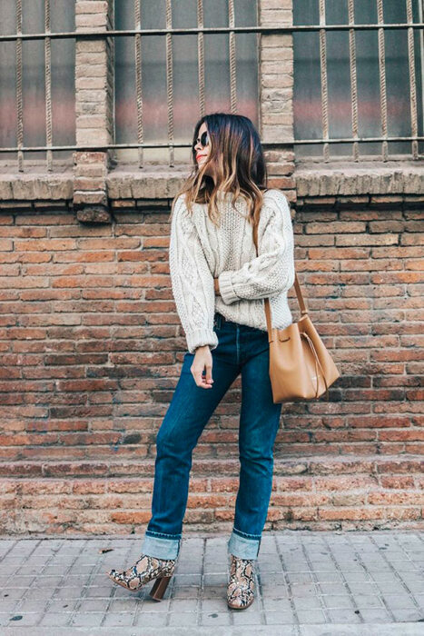 Chica usando botas pitón con jeans, suéter color beige y bolso color caqui
