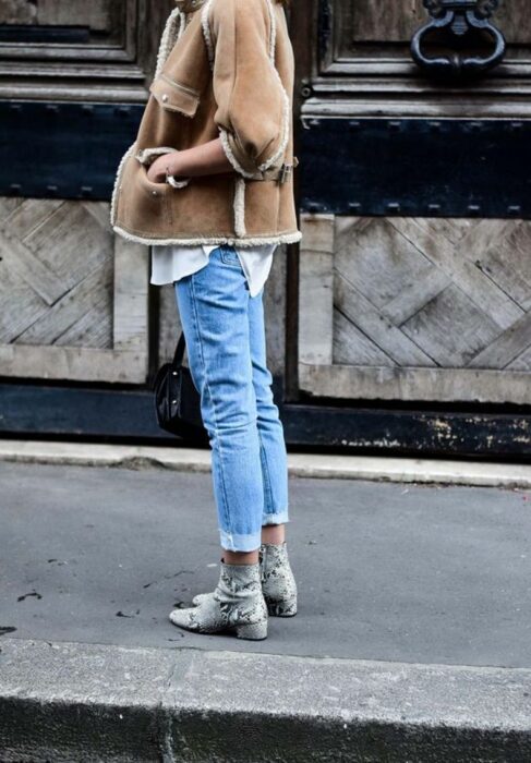Chica usando botas pitón con jeans, camisa y chaqueta de color caqui