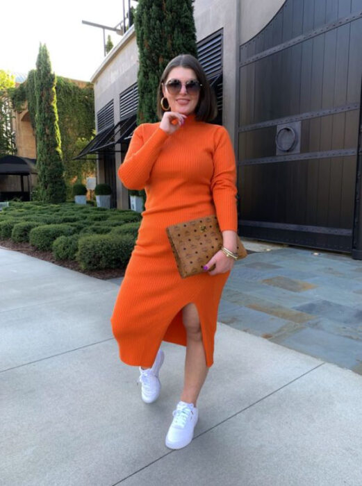 Mujer curvy luciendo un vestido naranja, con tenis blancos