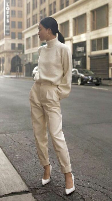 Chica luciendo un total white look con tacones, pantalón de vestir y un suéter de cuello alto y mangas abullonadas