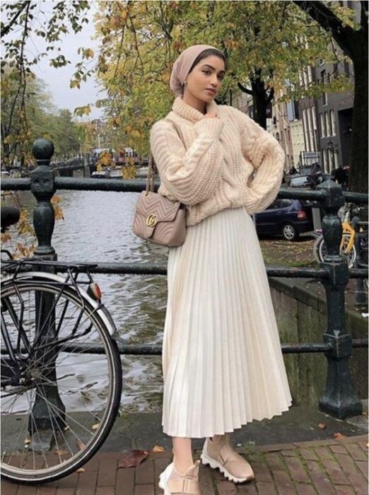 Chica con un total white look que incluye tenis, maxi falda, suéter de cuello alto y mangas abullonadas