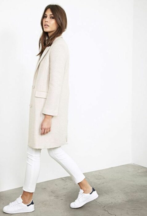 Chica usando un total white look con tenis, jeans y un blazer largo