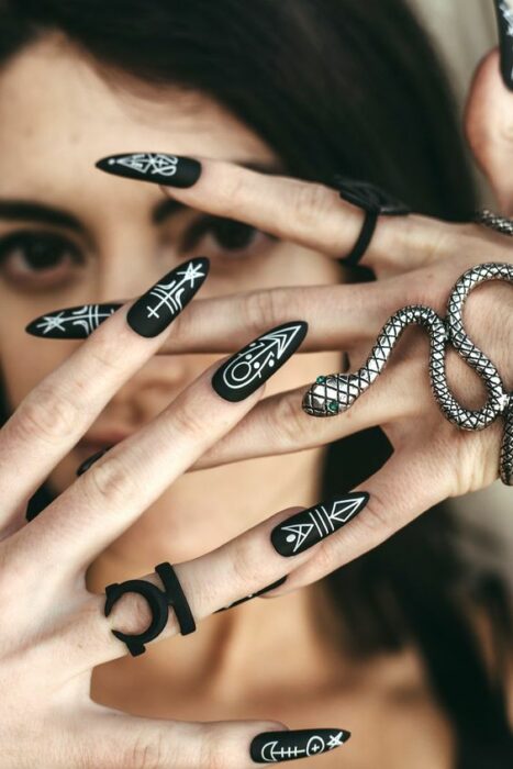 Chica con uñas negras con estampados blancos de serpientes y símbolos; Uñas para chicas que aman el ocultismo