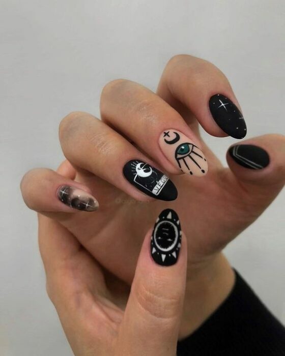 Chica con uñas en negro y pastel con estampados blancos; Uñas para chicas que aman el ocultismo