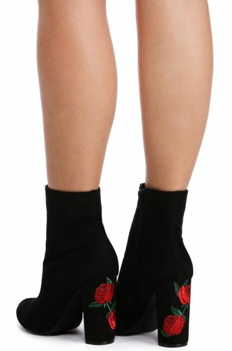 mujer con botines altos y negros, adornados con bordados de flores rojas en el tacón; 13 Zapatos bordados que te gustaría tener en tu guardarropa