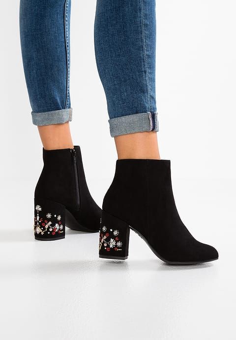 mujer con botines cortos, tacón bajo decorado con flores en tonos verdes y rojos; 13 Zapatos bordados que te gustaría tener en tu guardarropa