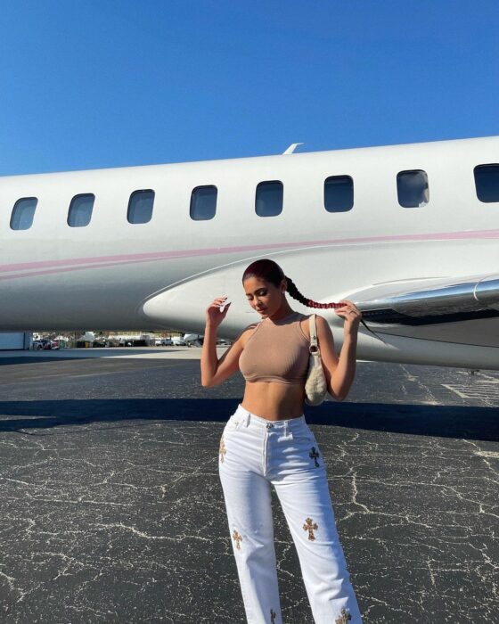 Kylie Jenner posando para una fotografía frente a un avión antes de viajar