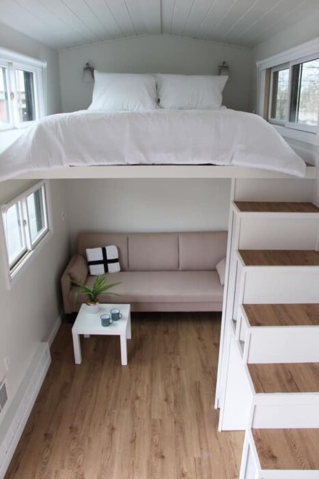 Mini casa con piso de madera y una cama matrimonial