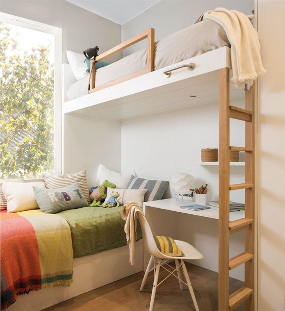 Habitación con cama alta y escritorio junto a escaleras de madera