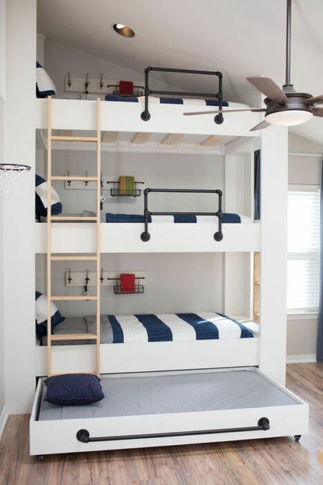 Cama de tres pisos blanca con cobijas blancas y rayas azules