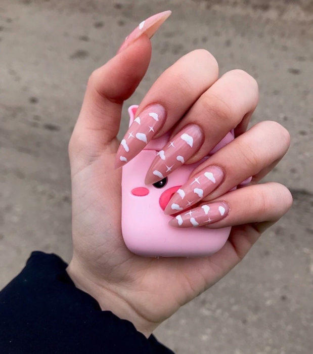 Manicura con diseño de cielo y nubes; uñas largas stiletto pintadas con esmalte rosa bebé
