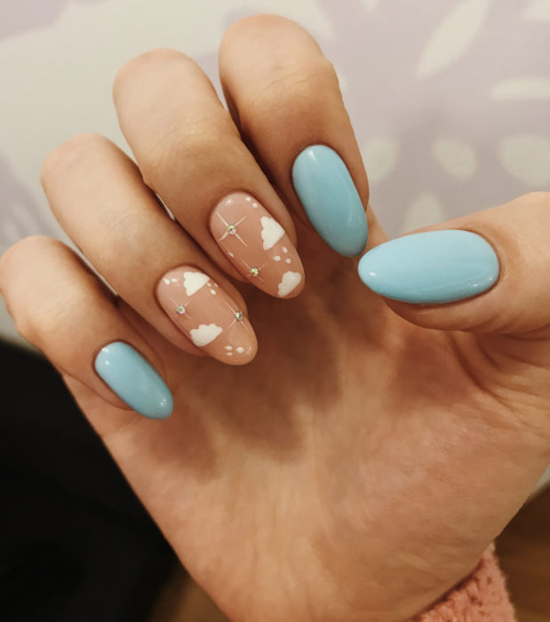 Manicura con diseño de cielo y nubes; uñas en forma de almendra pintadas con esmalte azul y nude
