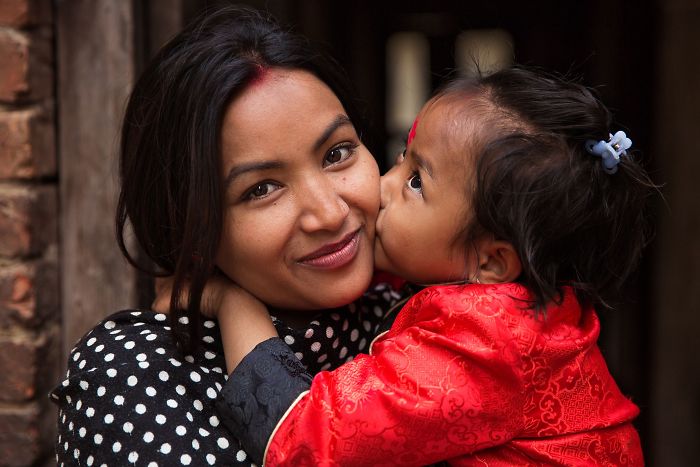 Fotografía de Mihaela Noroc, bebé dando un beso en la mejilla a su mamá