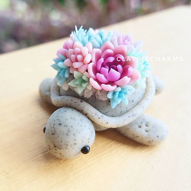 Tortuga gris con suculentas rosas, lilas y azules hecha con arcilla polimérica