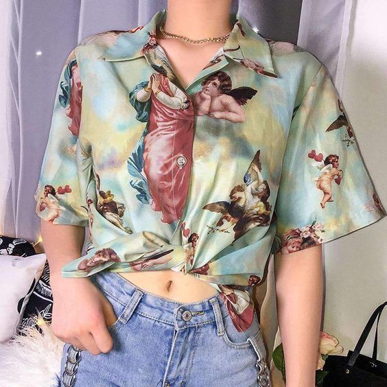 Chica con camisa verde con estampado de ángeles con pantalón de mezclilla