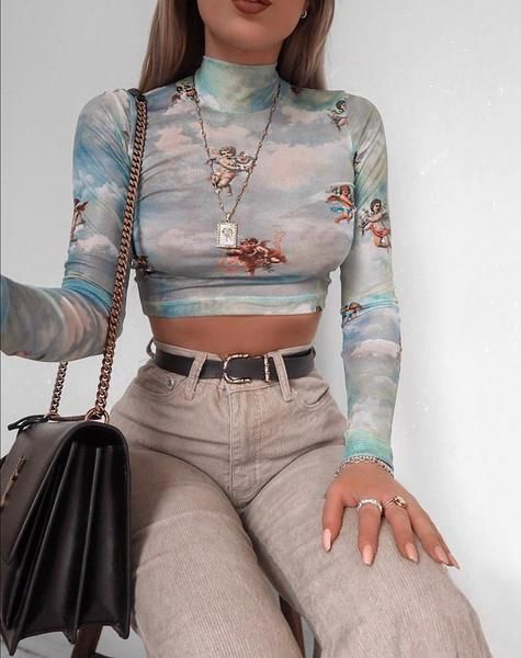 Chica delgada con crop top de manga larga color azul con estampado de ángeles y pantalón beige