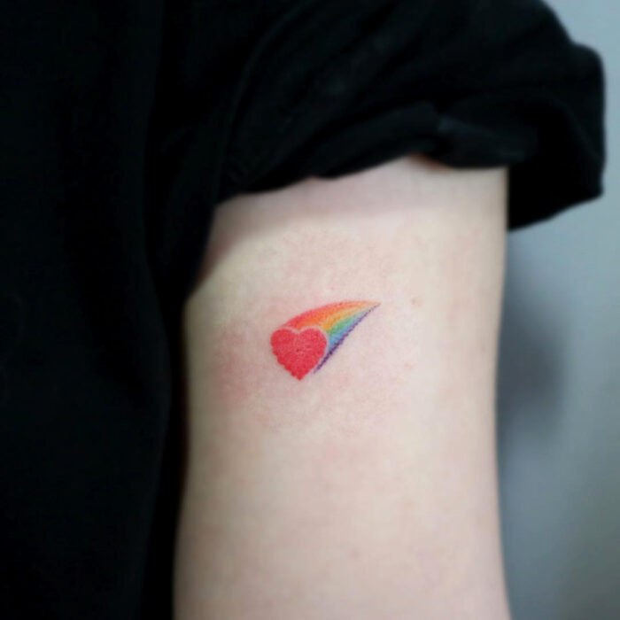 Diseños adorables de tatuajes de arcoíris con corazón en el brazo