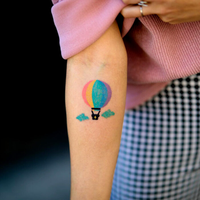 Diseños vibrantes de tatuajes de globo aerostático de arcoíris en el brazo