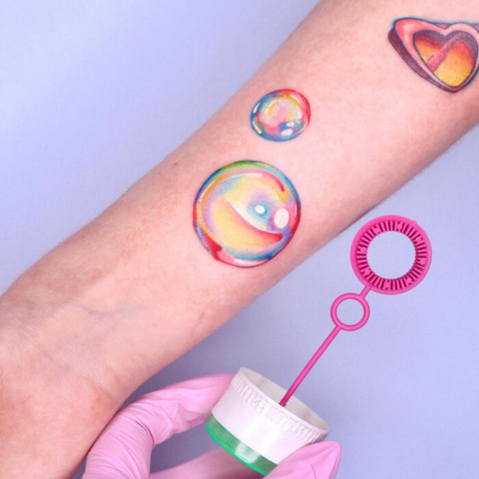 Diseños llamativos de tatuajes de burbuja de jabón de arcoíris en el brazo