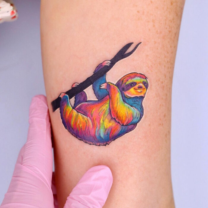 Diseños únicos de tatuajes de oso perezoso de colores arcoíris en el brazo