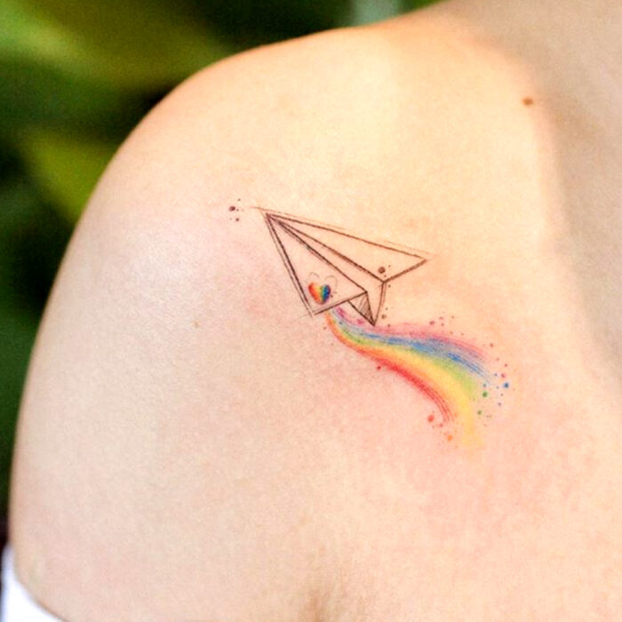 Diseños encantadores de tatuajes de avión de papel de arcoíris en el hombro