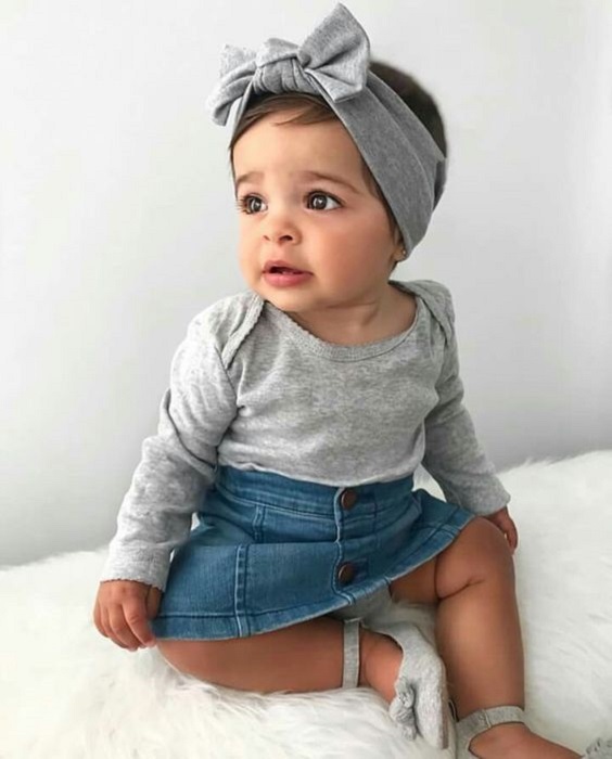 Bebé usando blusita gris, con faldita y diadema
