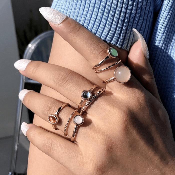 anillos dorados con piedras redondas de color rosa, azul y blanco