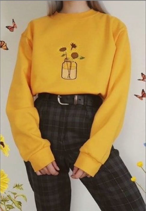 Chica llevando sudadera amarilla con bordado de girasoles